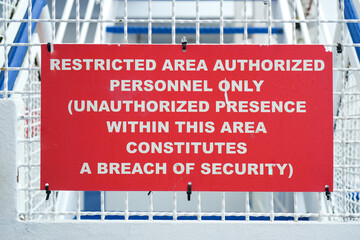 Close-Up Horizontal Frame of a Red Restricted Area Authorized Personnel Only Warning Sign on a White Metal Fence. Security Concept