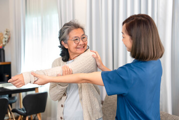 Fototapeta premium asian senior woman doing physiotherapy that support from a young female nurse,asian older adult having rehab arm stretching at home,concept of elderly lifestyle,home care,home health care