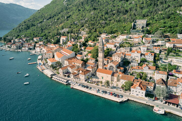 Fototapeta na wymiar Aerial view of the ancient bell tower of the Church of St. Nicholas among the red roofs of houses. Perast, Montenegro