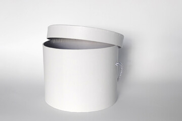 Single blank textured round box, gift with rope and its lid lean on it isolated on light white...