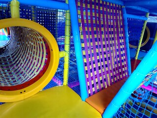 Entrance to the labyrinth with colorful tunnel and bridges, children's room in play Entertainment center. Floor, steps to trampoline. Banner active leisure, free time kids photo. Cozy play area
