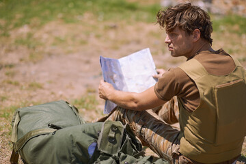 Soldier with map on battlefield, planning battle location or tactical operation goals for mission...