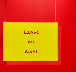 Yellow hanging sign with text written LEAVE ME ALONE on red background -  refrain from disturbing,...
