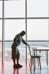 Young pregnant woman at work in the office standing near the window. Work during pregnancy. Pregnant business lady