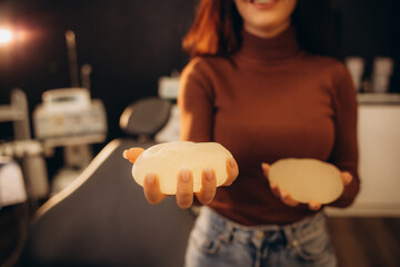Female hand squeezing soft round breast implant. Isolated, clipping path.