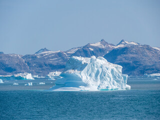Eisberg in einem grönländischen Fjord mit Berge im Hintergrund