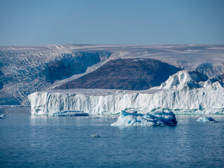 Eisberg in einem grönländischen Fjord mit Gletscher im Hintergrund