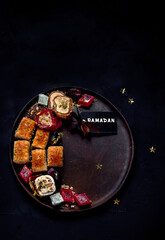Obraz na płótnie Canvas Ramadan food on a large plate. Arabic sweets - lokum, fruit marmalade, baklava on a black background