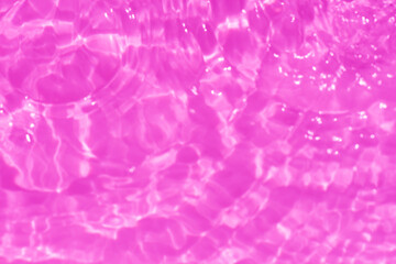 Pink water splashes on the surface ripple blur. Defocus blurred transparent purple colored clear calm water surface texture with splash and bubble. Water waves with shining pattern texture background.