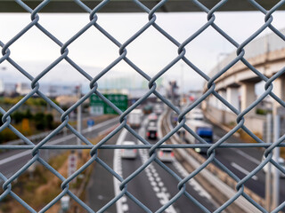 歩道橋のフェンス越しに見る高速道路の風景