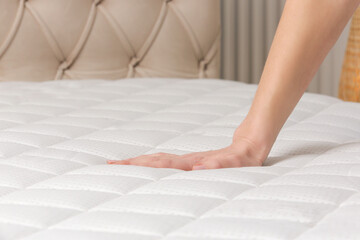 Woman press on comfortable mattress, checking and testing quality