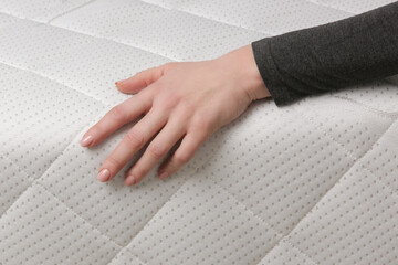 Woman press on comfortable mattress, checking and testing quality