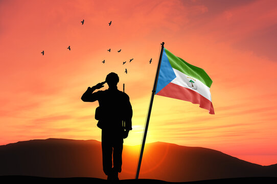 Silhouette of a soldier with the Equatorial Guinea flag stands against the background of a sunset or sunrise. Concept of national holidays. Commemoration Day.