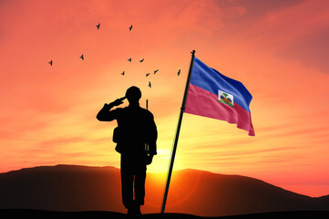 Silhouette of a soldier with the Haiti flag stands against the background of a sunset or sunrise. Concept of national holidays. Commemoration Day.