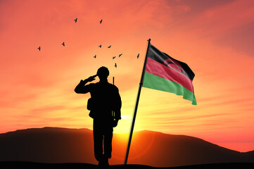 Silhouette of a soldier with the Malawi flag stands against the background of a sunset or sunrise. Concept of national holidays. Commemoration Day.
