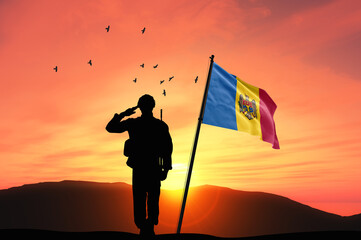 Silhouette of a soldier with the Moldova flag stands against the background of a sunset or sunrise. Concept of national holidays. Commemoration Day.