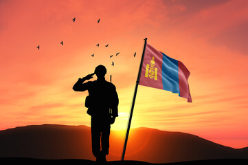 Silhouette of a soldier with the Mongolia flag stands against the background of a sunset or sunrise. Concept of national holidays. Commemoration Day.
