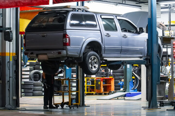 Pickup truck lifted into the air using a mechanical bridge jack in a service garage for car repair...