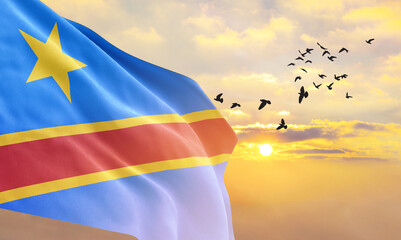 Waving flag of DR Congo against the background of a sunset or sunrise. DR Congo flag for...
