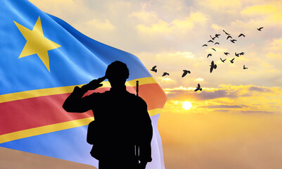 Silhouette of a soldier with the DR Congo flag stands against the background of a sunset or...