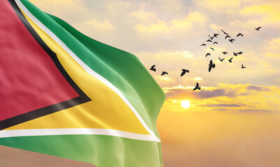 Waving flag of Guyana against the background of a sunset or sunrise. Guyana flag for Independence Day. The symbol of the state on wavy fabric. - obrazy, fototapety, plakaty