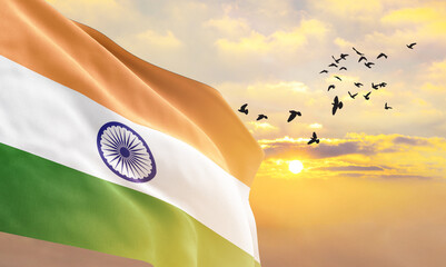 Waving flag of India against the background of a sunset or sunrise. India flag for Independence Day. The symbol of the state on wavy fabric. - obrazy, fototapety, plakaty