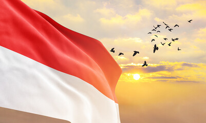 Waving flag of Indonesia against the background of a sunset or sunrise. Indonesia flag for Independence Day. The symbol of the state on wavy fabric. - obrazy, fototapety, plakaty