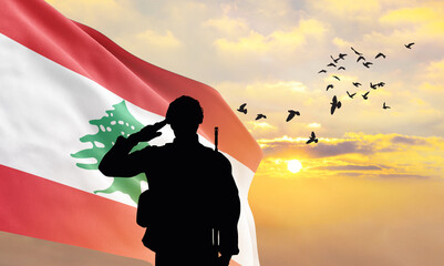 Silhouette of a soldier with the Lebanon flag stands against the background of a sunset or sunrise....