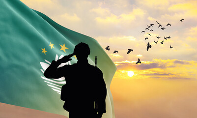 Silhouette of a soldier with the Macao flag stands against the background of a sunset or sunrise....