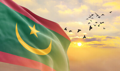 Waving flag of Mauritania against the background of a sunset or sunrise. Mauritania flag for...