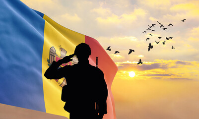 Silhouette of a soldier with the Moldova flag stands against the background of a sunset or sunrise....