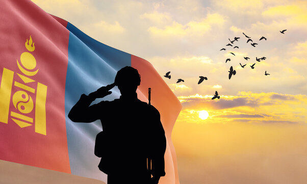 Silhouette of a soldier with the Mongolia flag stands against the background of a sunset or sunrise. Concept of national holidays. Commemoration Day.