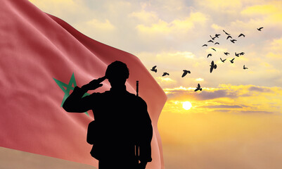 Silhouette of a soldier with the Morocco flag stands against the background of a sunset or sunrise....