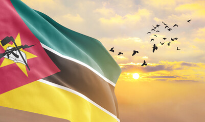 Waving flag of Mozambique against the background of a sunset or sunrise. Mozambique flag for...