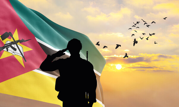 Silhouette of a soldier with the Mozambique flag stands against the background of a sunset or sunrise. Concept of national holidays. Commemoration Day. - Powered by Adobe