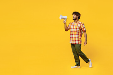 Full body young Indian man he wears shirt casual clothes hold in hand megaphone scream announces discounts sale Hurry up isolated on plain yellow color background studio portrait. Lifestyle concept.