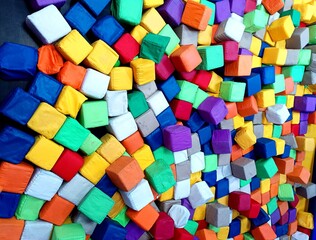 Dry pool with colorful soft cubes photography. Mix little poof on trampoline blue red yellow brown purple green. Print pattern design abstract background. Children's game room 