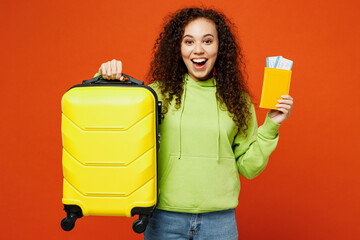 Traveler happy woman wear green casual clothes hold passport ticket bag isolated on plain orange...