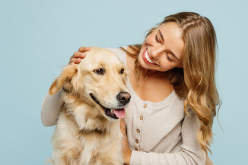 Young smiling happy owner fun woman with her best friend retriever wears casual clothes scratch and hug cuddle dog isolated on plain pastel light blue background studio. Take care about pet concept.