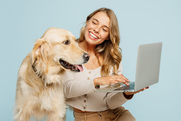 Young happy owner IT woman with her best friend retriever dog wear casual clothes hold use work on...