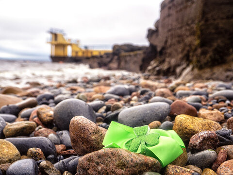 Green bow with shamrock on a rock by Blackrock diving tower, Salthill area, Galway city, Ireland. Popular city landmark and tourist viewpoint with stunning nature scenery. Vertical image.
