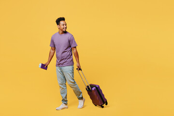 Traveler man he wears casual clothes hold bag passport ticket go look aside isolated on plain yellow background. Tourist travel abroad in free spare time rest getaway. Air flight trip journey concept.
