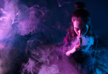 Woman vaper. Girl using vape device. Lady with electronic cigarette. Female student is vaping. Vape pen in hands of woman. Vaper in smoke from electronic cigarette. Girl with vape hobby. - obrazy, fototapety, plakaty
