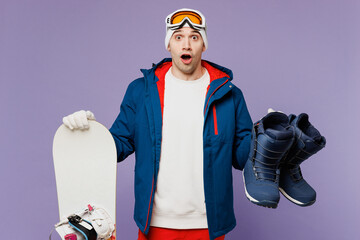 Shocked surprised amazed man wears warm blue windbreaker jacket ski goggles mask hat hold in hand...