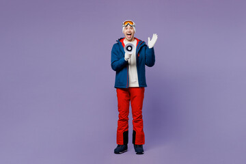 Full body young skier man wear warm blue windbreaker jacket ski goggles mask hat scream in megaphone about sales spend extreme weekend winter season in mountains isolated on plain purple background.