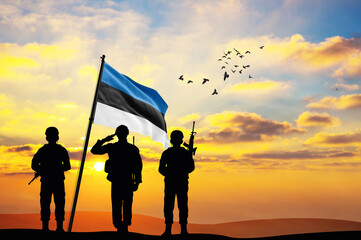 Silhouettes of soldiers with the Estonia flag stand against the background of a sunset or sunrise. Concept of national holidays. Commemoration Day.