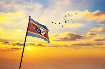 Waving flag of Eswatini against the background of a sunset or sunrise. Eswatini flag for...