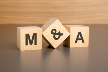 M and A letters on wooden cubes against brown background with copy space. concept of sale and discount.