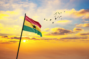 Waving flag of Ghana against the background of a sunset or sunrise. Ghana flag for Independence Day. The symbol of the state on wavy fabric. - obrazy, fototapety, plakaty
