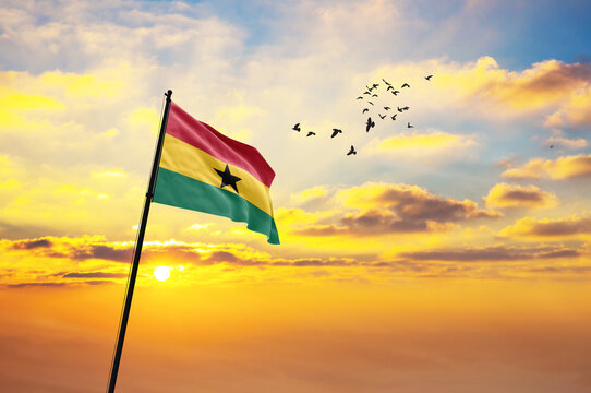 Waving flag of Ghana against the background of a sunset or sunrise. Ghana flag for Independence Day. The symbol of the state on wavy fabric. - Powered by Adobe